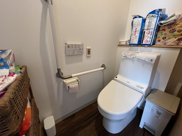 落ち着いた色合いのトイレ トイレ   広々とした清潔感のある空間で、手すり付きの設備が安心感を提供します。