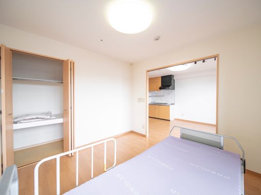 幅の広い収納スペースを備えた室内にベッドが置かれている。その奧に、更に広い部屋があり、システムキッチンが設置してある。
