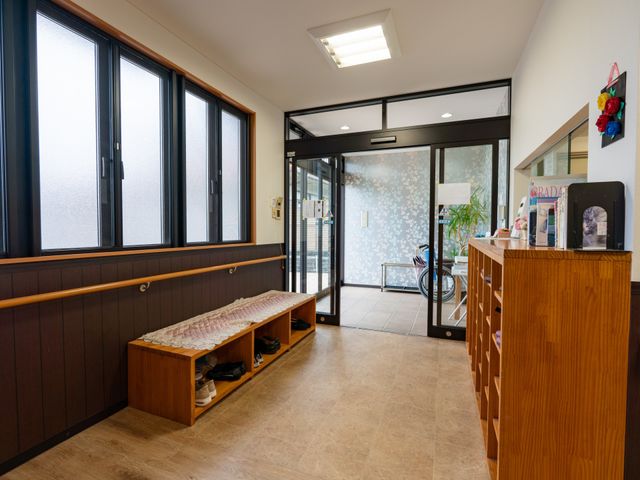 明るい玄関ホール エントランス   大きな窓から光が入る、明るく落ち着いた出入り口です。ベンチや靴箱があり、来訪者を迎えやすい雰囲気です。