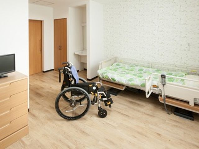 車椅子のある居室 居室   車椅子が置かれた明るい居室です。ベッドやテレビがあり、落ち着いて過ごしやすい空間です。