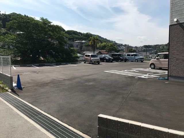 駐車スペースが広い外観 駐車場 広々とした駐車場が完備されており、来訪者の利便性を考慮した構造になっています。日当たりが良く、緑も見える開放的な環境です。