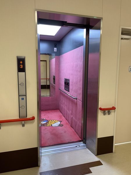 ピンクの広々とした乗り場のエレベーター