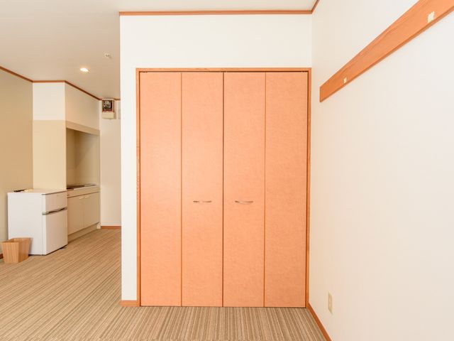 居室のクローゼットとキッチン 居室 温かみのある色合いの居室には、収納豊富なクローゼットと実用的なキッチンが備わっており、快適な生活空間が広がっています。