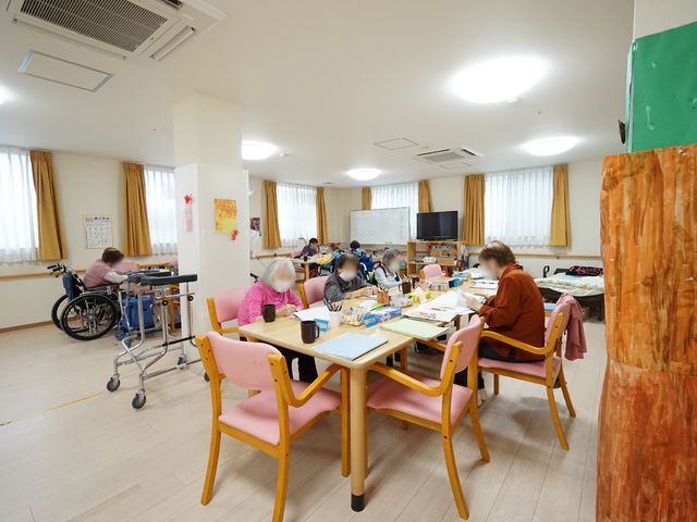 多様な活動を楽しむ多目的室 共有スペース 柔らかい光が注ぐ部屋で、利用者の方々が様々な創作活動に熱中しています。手作業を通じて、コミュニケーションも楽しむことができる空間です。