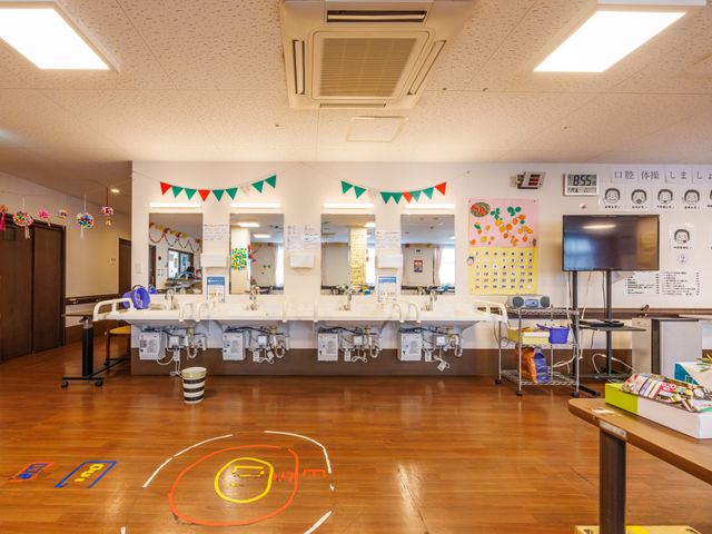 明るい洗面スペース 洗面台   横並びの洗面台があり、鏡の前で身支度や口腔ケアの確認がしやすい空間です。壁面の掲示も見やすく、日々の支援に使いやすそうです。