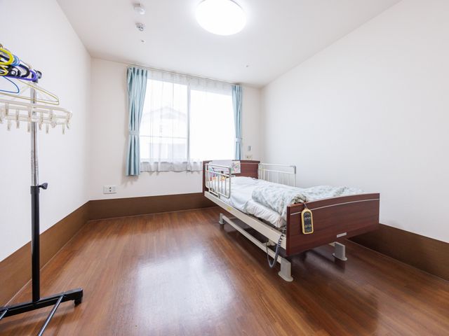 明るい居室のベッド 居室   大きな窓から光が入り、床や壁がすっきりとした居室です。ベッド周りにゆとりがあり、介助や見守りがしやすそうです。