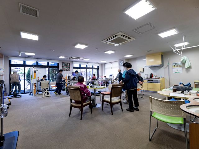 活動的な共有スペース 機能訓練室 広々とした多目的室では、利用者が様々な活動を楽しんでいます。明るく開放感のある空間が印象的です。