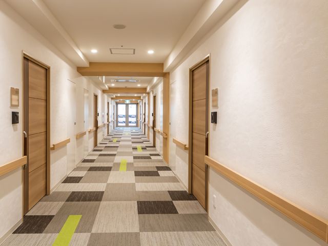 明るく清潔な廊下の風景 廊下 床には配色が施されたカーペットがあり、安全かつ快適な移動を支援します。廊下も広々としており、快適な職場環境でしょう。
