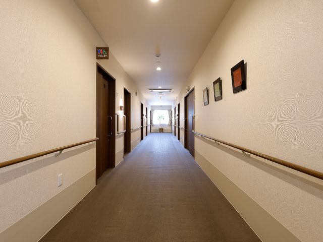 明るい廊下の風景 廊下 広々として明るい通路は、壁に手すりが設置され、安全に歩行できるよう配慮されています。