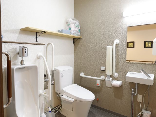 バリアフリー設計のトイレ トイレ 手すり付きの清潔なトイレスペースです。利用者の安全と快適さを考えた配慮が整っており、日々の生活をサポートします。