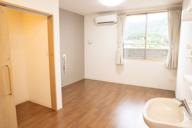 明るい居室の一角 居室 広々とした空間の居室からは、窓越しに自然景色が望め、心安らぐ環境です。快適なエアコン設備も完備されております。