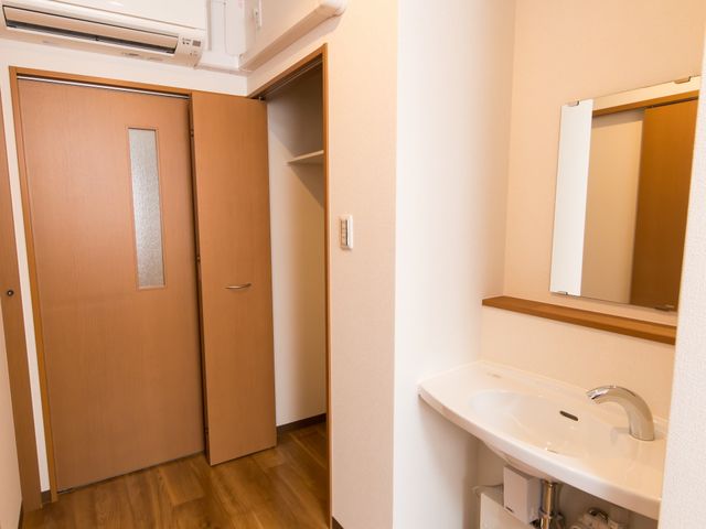 清潔感のある洗面所 居室 機能的な壁掛け型洗面台と、シンプルなデザインの鏡が備え付けられたスペースです。利用者の日々の準備に寄り添う設計になっています。