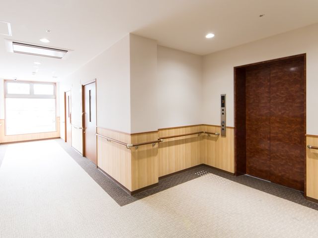 明るい廊下の一角 通路 ゆとりある通路は、光がたっぷりと注ぎ込み、清潔感のある環境です。壁沿いの手すりが安全な歩行を支えます。