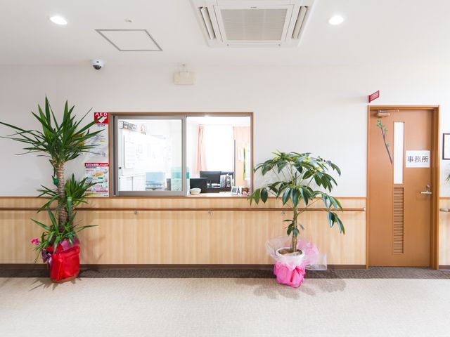 清潔な施設のフロント 受付 温かみのある木目調のフロントが迎えてくれる、清潔感溢れる応接空間です。笑顔でお出迎えするスタッフが、安心の日々を支えてくれます。
