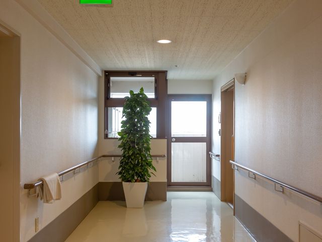 明るい中庭が見える廊下 通路 手すり付きで安全性を考慮した廊下は、採光を取り入れた設計で居心地の良い移動空間を提供します。