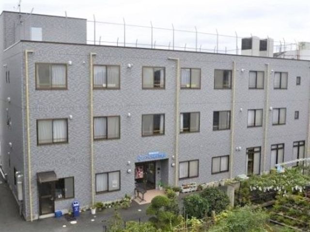 施設の外観を示す 外観 閑静な環境に佇む明るい建物は、訪れる方々を暖かく迎え入れます。入口には植物が並び、自然に囲まれた癒しの空間が広がっています。