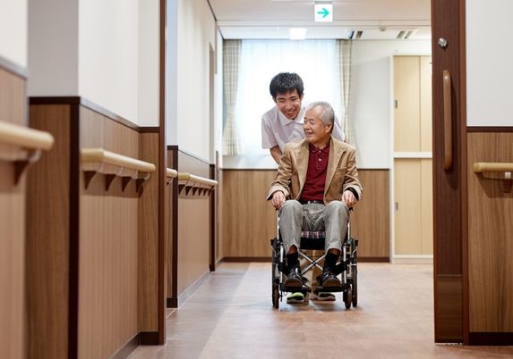 車椅子の男性とスタッフ 廊下