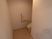 サムネイル L字スペースの奥にトイレがあり、その横の壁に手すり、ペーパーホルダー、オレンジ色の緊急用コールボタンが付いている。