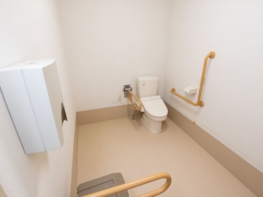 ベージュと白でまとめられた落ち着いた雰囲気のトイレである。温水洗浄機能付きトイレの横には、緊急用呼び出しボタンがある。