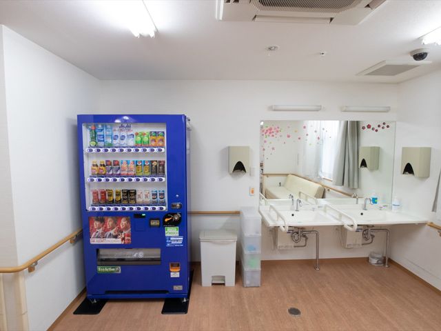清潔な洗面台と自動販売機 自動販売機 ゆとりのある洗面スペースには、便利な飲み物の自動販売機も設置されています。入居者の生活を考えた配慮が感じられる環境です。