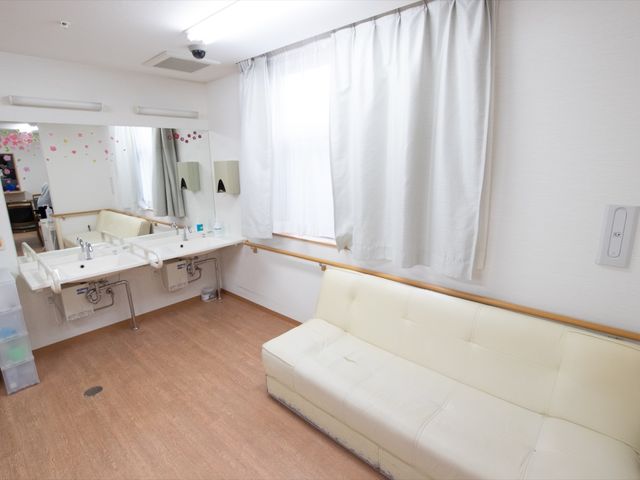 洗面台とソファのある部屋 洗面台 明るく清潔感に満ちた洗面スペースです。余裕のあるソファでゆったりお過ごしいただける様子がうかがえます。