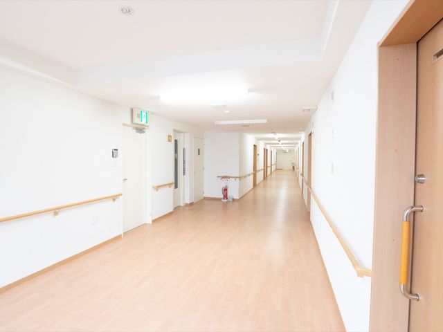 清潔な長い廊下 廊下 手すりが設置された広々とした廊下は、明るく清潔感があります。ここを通る毎日が、ご利用者様にとって快適で安心な時間を提供しています。
