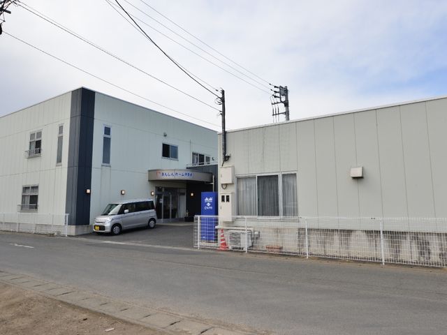 青灰色の建物の外観 施設の外観 ゆったりとした敷地に建つ青灰色の建物は、落ち着いた雰囲気を提供しています。清潔感のある入口からのアクセスも良好です。