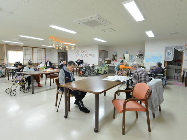 活気ある共有スペース 談話室 多世代が集う食堂では、日々の暮らしの中でコミュニケーションを育む場が確保されています。ゆとりあるテーブル配置で、それぞれの時間を過ごす方々の姿が見られます。