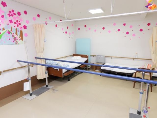 機能訓練室の明るい空間 機能訓練 広々とした明るい空間で、個々の生活スタイルに合わせた機能訓練が受けられます。カラフルな装飾が施された室内は、リハビリを行う方々のやる気を後押ししています。