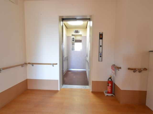 廊下とエレベーターの空間 内観 手すりが備わった廊下は、安全に移動ができる設計です。エレベーターへのアクセスもすぐ傍にあります。