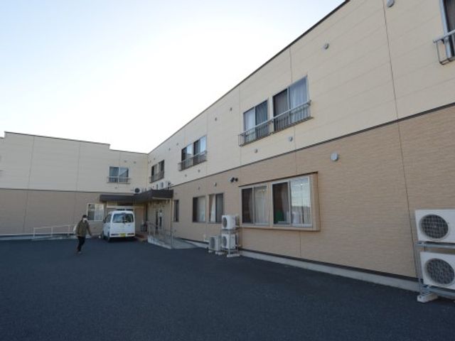 建物外観と駐車スペース 外観 広々とした駐車スペースがあり、利用者の方の送迎時も安心です。職員の方々の動線にも配慮された設計となっております。