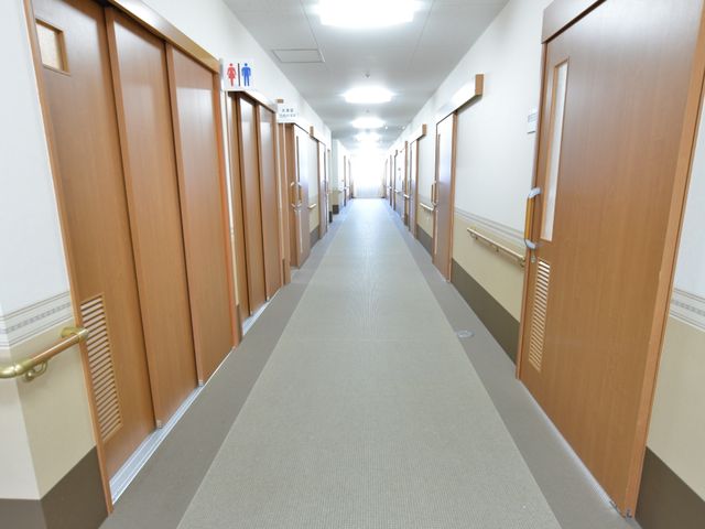 廊下の清潔感ある空間 共有廊下 手すり付きの広く明るい廊下です。従業員の方々の移動もスムーズで、安全に配慮された設計となっています。