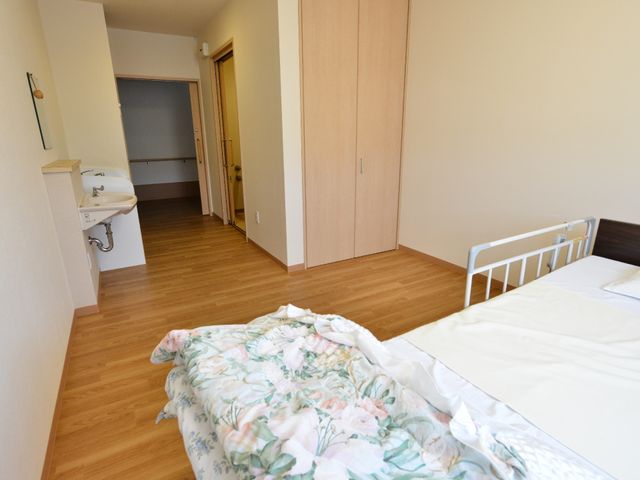 居室のすっきりとした内観 居室から廊下方面を見た様子 ゆとりのある清潔感のあふれる個室です。ベッドや手洗い設備も整い、快適な日々を過ごせる環境が整備されています。