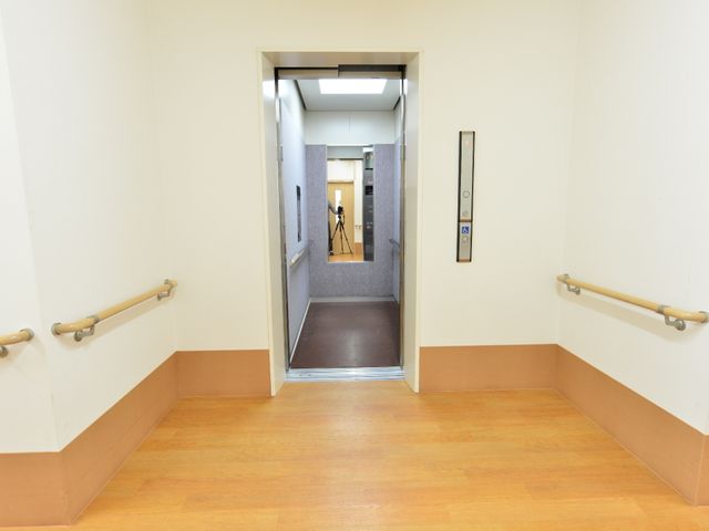 廊下の安全手すり エレベーターの手すり 手すりが設置された明るい廊下は、すれ違う人たちが安全に移動できるよう配慮されています。