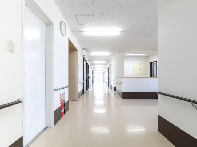 清潔な施設の廊下 廊下 明るく清潔感のある通路が広がっており、壁面の手すりが利用者の移動をサポートします。ゆったりとした造りは、働く環境の快適さを感じさせます。