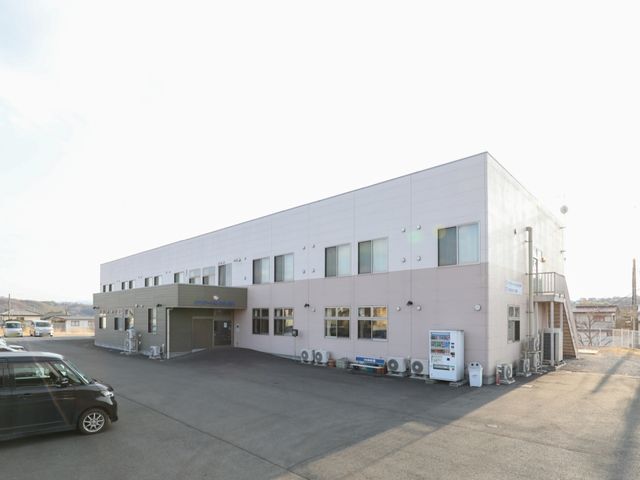 白い建物の外観 外観 清潔感のある建物は広々としており、朝日を浴びて輝いています。オープンな雰囲気が仕事にも前向きな印象を与えます。