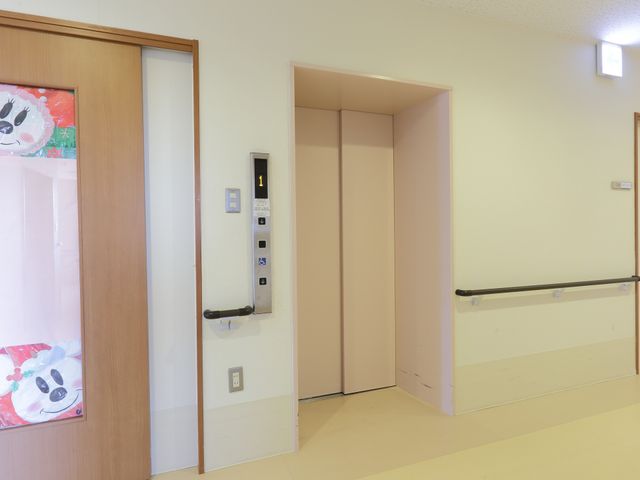 廊下にあるエレベーター エレベーター 清潔感のある廊下に設置されたエレベーターは、利用者の利便性を高めています。壁に手すりがあり、安全に配慮されています。