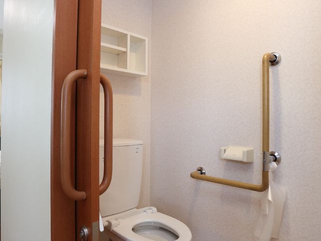 手すり付きトイレの一角 トイレ 手すりが設置された清潔なトイレです。安全性を重視し、どなたでも安心してご使用いただける設計になっています。