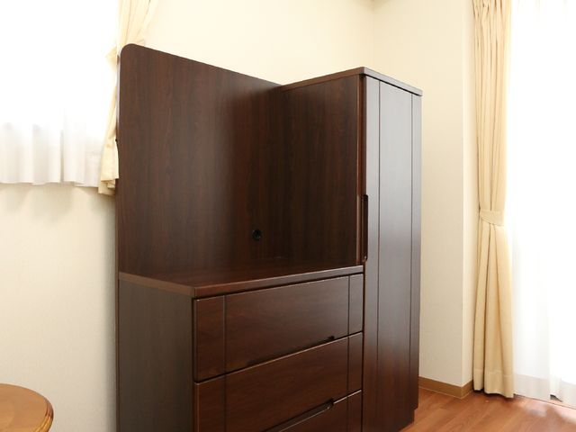 整頓された茶色の洋室 居室  落ち着いた色合いの家具が置かれた、清潔感のある居室です。日差しも入り明るく、快適な生活空間を実現しています。