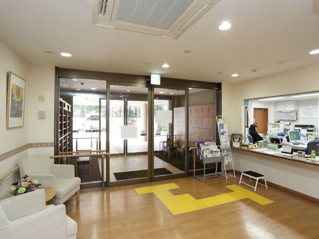 エントランスの明るいロビー 玄関ホール ゆったりとしたロビーは、自然光が差し込む心地よい空間です。フロントでは、職員が日々の対応に勤しんでいます。