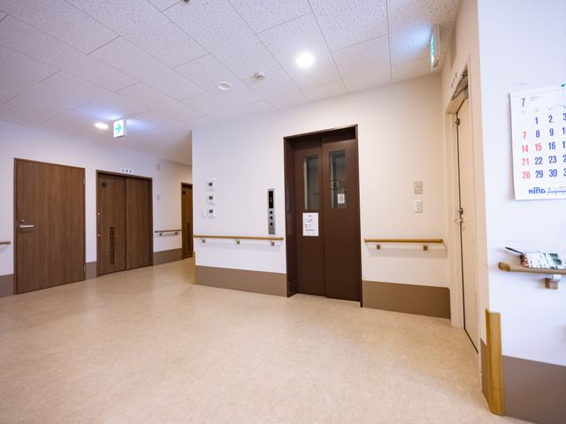 廊下の落ち着いた雰囲気 廊下 広々とした廊下は、手すりが整備されゆったりとした歩行が可能です。壁にはカレンダーや掲示物があり、情報共有の場となっています。