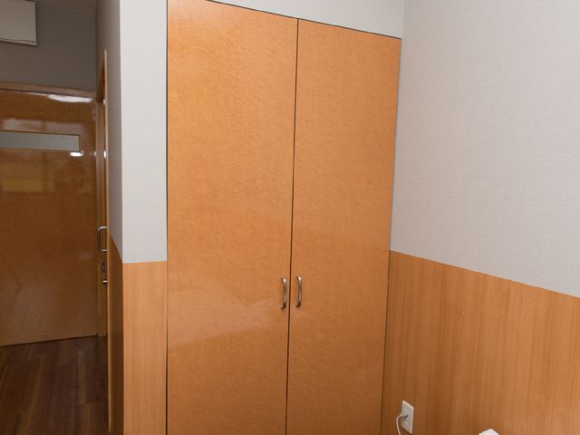 居室の木製クローゼット クローゼット 温かみのある木目調のクローゼットが特徴の個室で、スタッフの方々が利用者様の快適な生活を支援しています。
