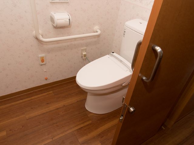 バリアフリーのトイレ設備 トイレ 手すり付きで安全に配慮されたトイレスペースです。清潔感のある環境で、利用者の快適さを考えた設計となっています。