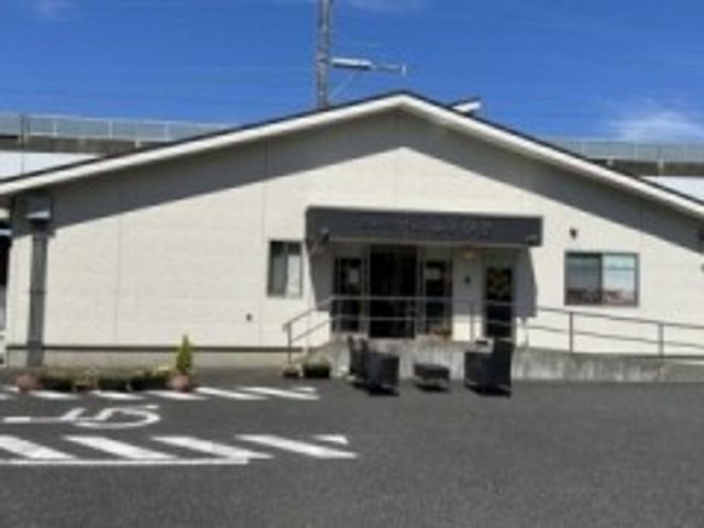施設の正面外観 外観   白い外壁の平屋建てで、入口前にスロープが見えます。車での来訪もしやすそうな、落ち着いた雰囲気です。