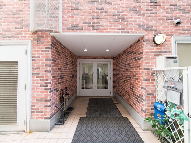 赤レンガのエントランス 外観 明るく開放的なエントランスは、訪れる方を温かく迎えます。清潔感のある通路を通り、毎日の勤務が始まります。