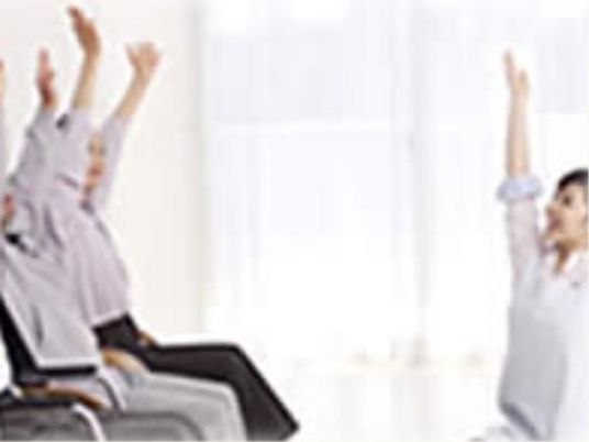 専門の職員が入居者様に機能訓練の授業を行っている様子である。椅子に座った状態でできる運動や簡単にできる運動などを提案している。