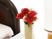ベッドの隣に置かれた花瓶。中には綺麗な花が生けられている。隣には照明がある。後ろは窓になっていて明るい。