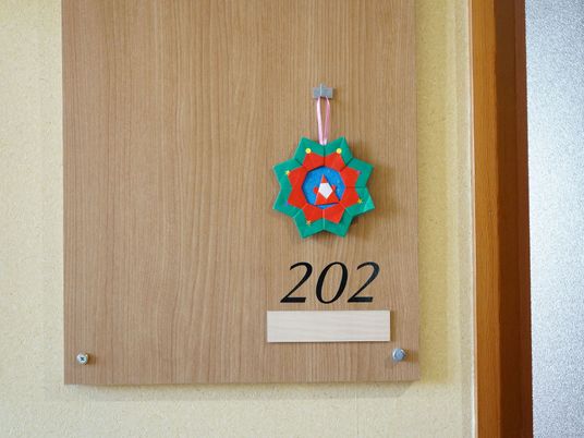 居室の前に付けられた部屋番号。数字の下には名前が表記できるようになっている。折り紙で作られた飾りを掛けてある。