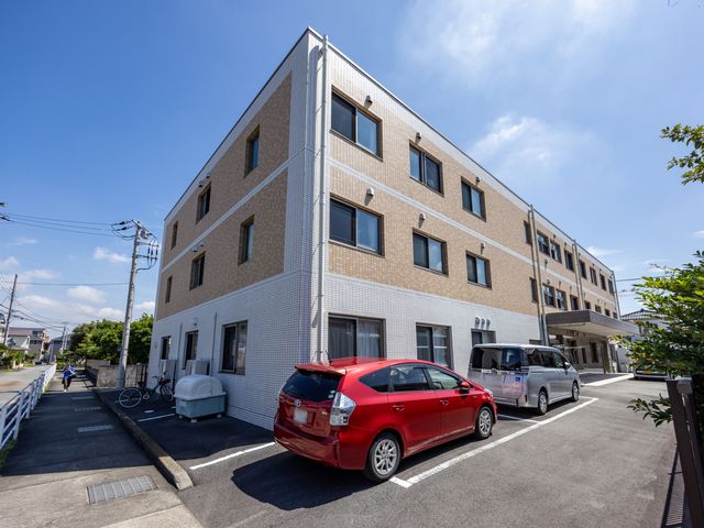明るい外観の建物 外観 広々とした門前の駐車スペースが印象的な建物です。併設された自転車置き場も便利です。