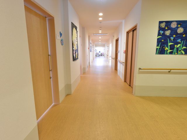 明るい広々とした廊下 廊下 温かみのある木目調のフロアが心地よい廊下が広がっており、壁に飾られたアートが空間に彩りを加えています。